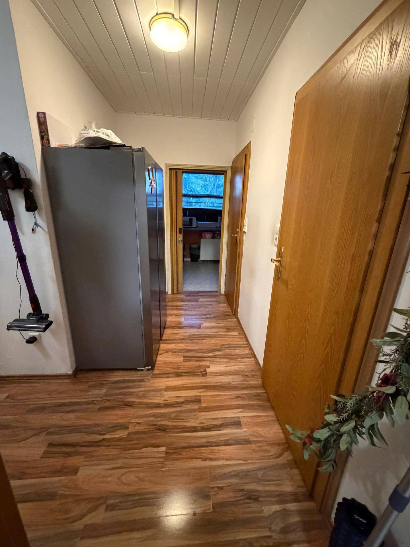Flur mit Holzfußboden und Blick in die angrenzende Küche.