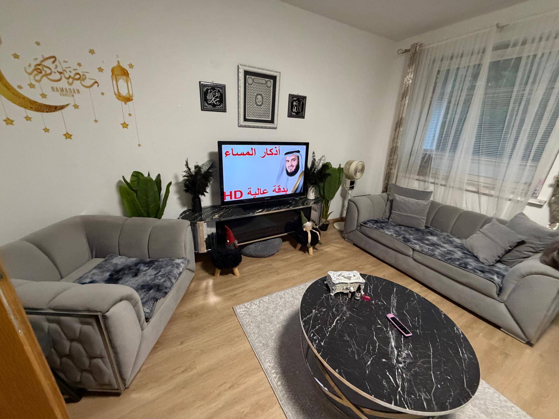 Gemütliches Wohnzimmer mit bequemen Sofas, Fernseher und dekorativen Wandelementen.