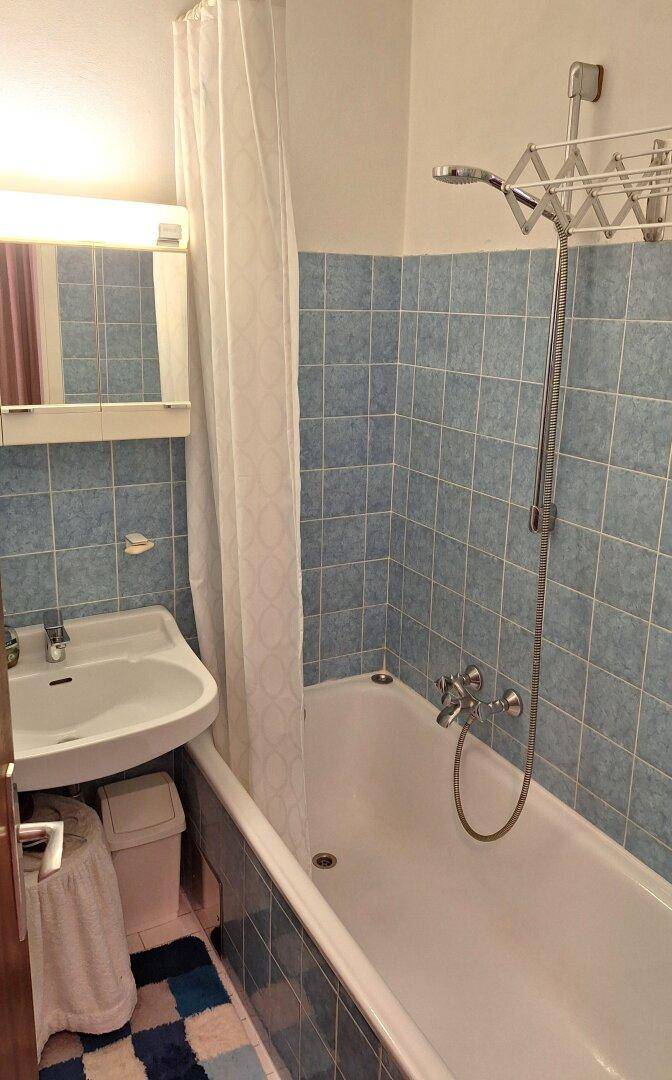 Badezimmer mit blauen Fliesen, Badewanne und Duschvorhang.
