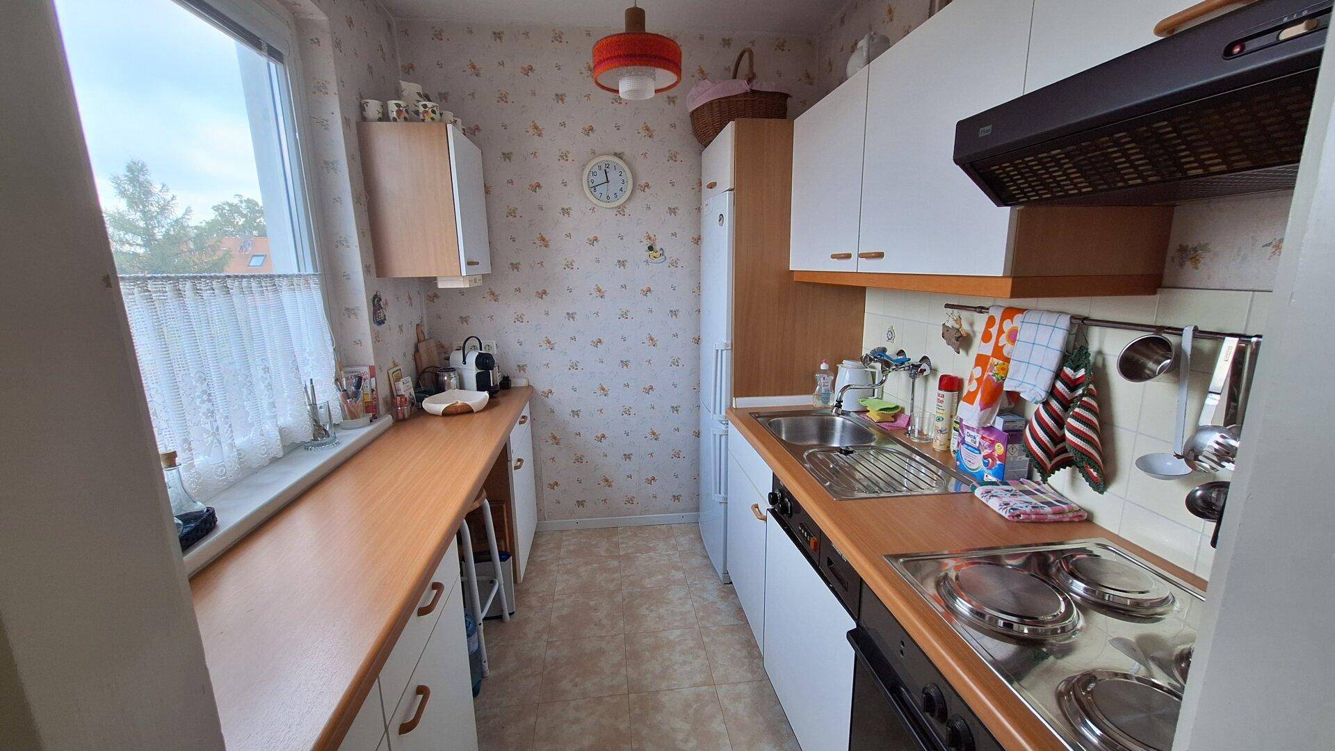 Kleine Küche mit funktionalen Geräten, Holz-Arbeitsplatte und Fenster.