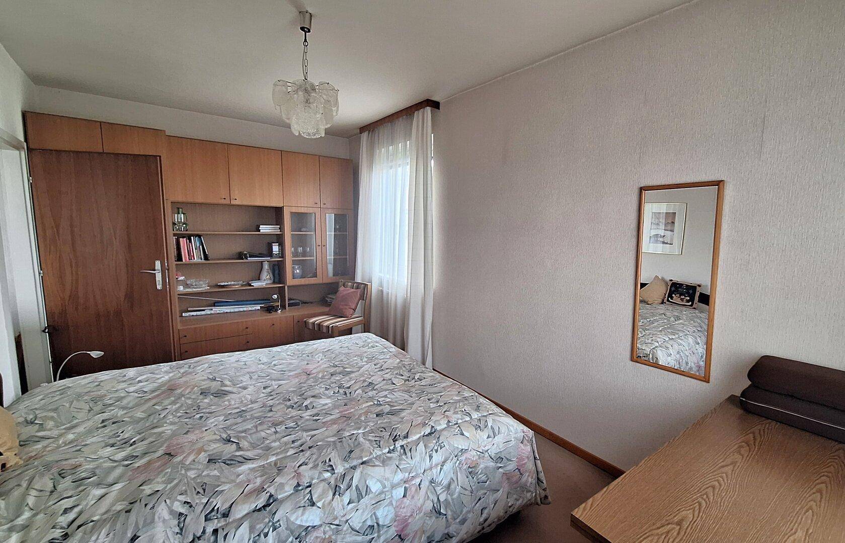 Schlafzimmer mit Doppelbett, Einbauschränken und hellem Teppichboden.