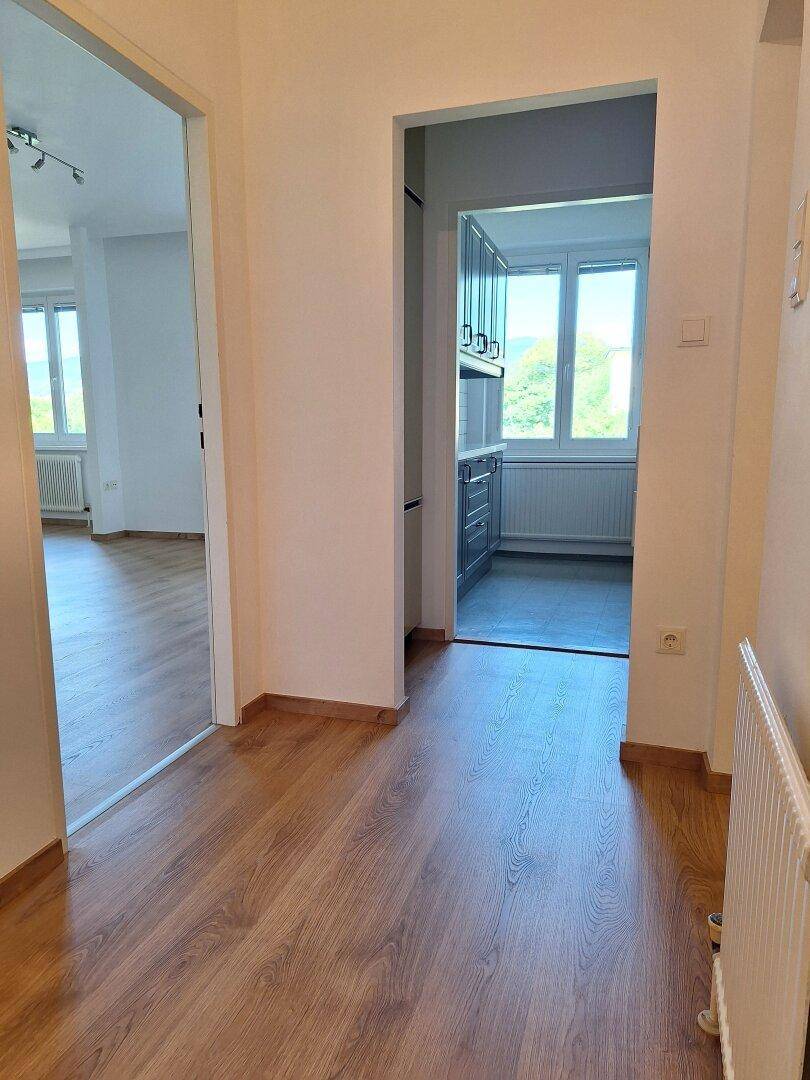 Heller Flur mit Laminatboden, der zum Wohnzimmer und zur Küche führt.