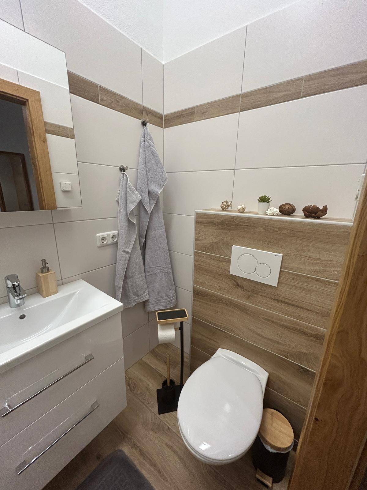 Modernes Gäste-WC mit Wand-WC, Waschbecken und stilvollen Holz- und Weißfliesen.