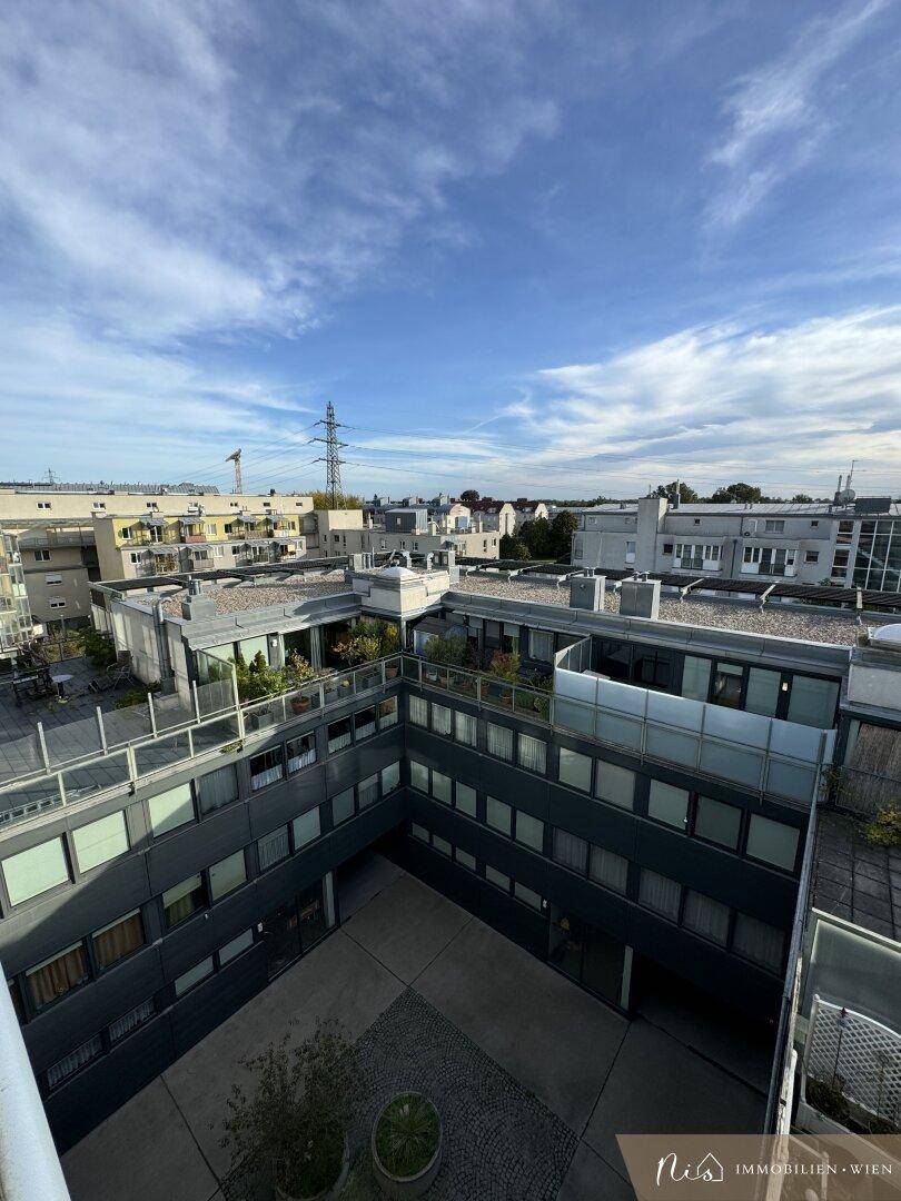 Blick von oben auf einen begrünten Innenhof mit modernen Gebäudefassaden und Dächern.