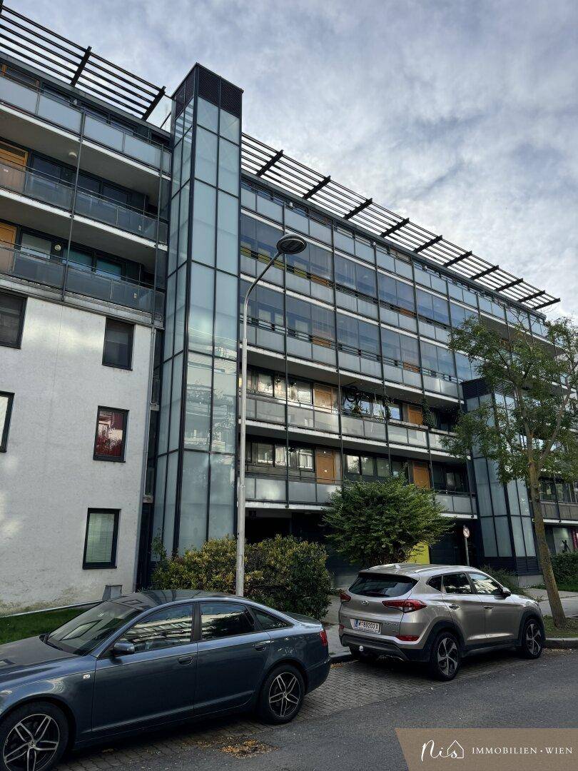 Moderne Gebäudefassade mit großen Glasflächen und Balkonen in urbaner Umgebung.