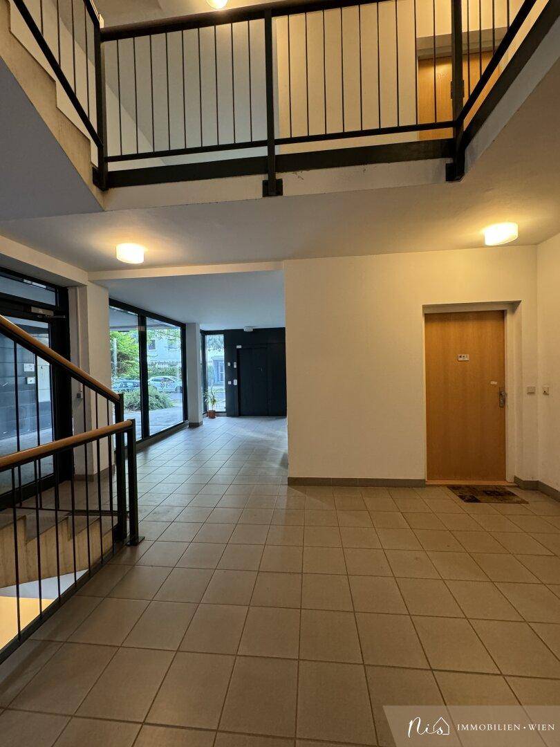 Heller Eingangsbereich mit Fliesenboden und Treppenhaus in einem modernen Gebäude.