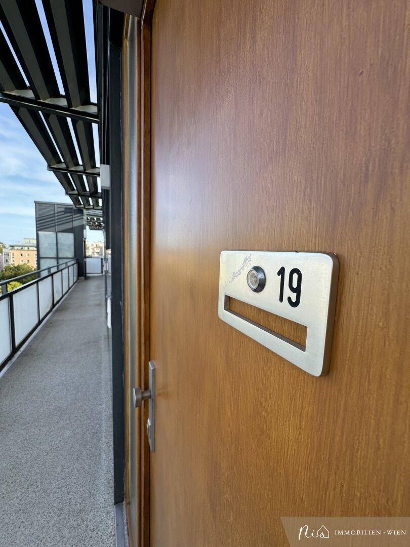 Eingangstür Nummer 19 zu einer Wohnung mit Zugang über einen Außengang.