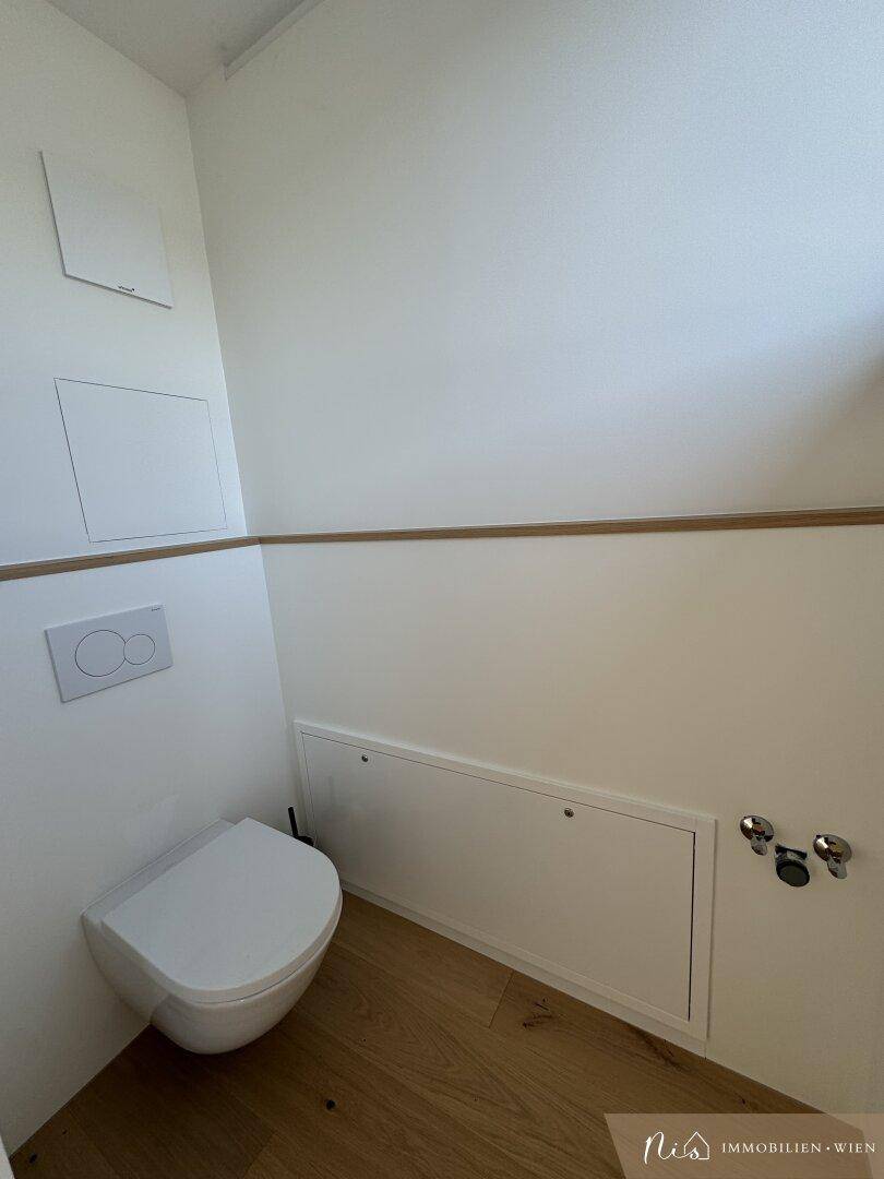 Modernes Gäste-WC mit wandhängender Toilette und Holzleiste.