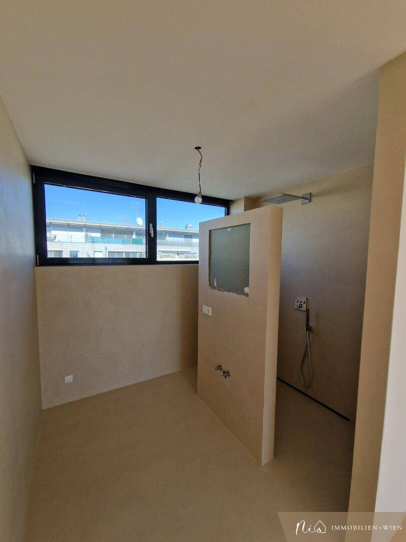 Unfertiges Badezimmer mit Fenster, vorbereitet für die Installation von Dusche und Waschtisch.