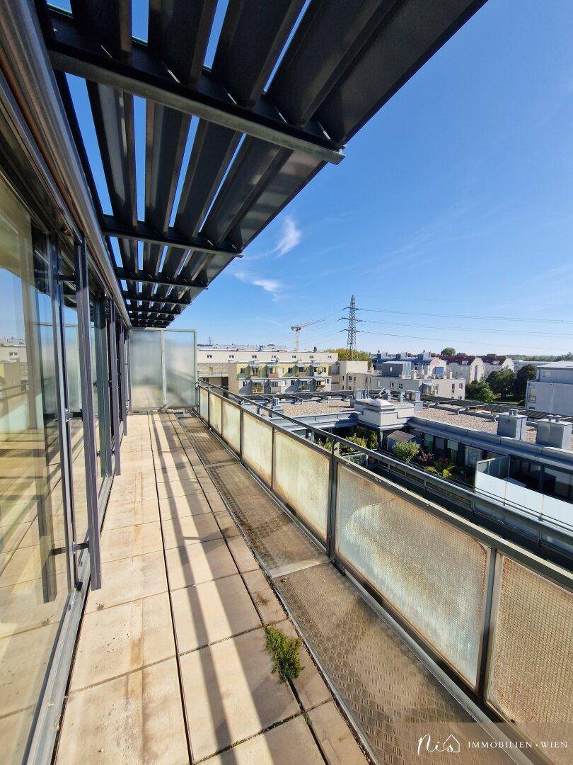 Geräumiger Balkon mit Fliesenboden und Glasgeländer, bietet viel Platz im Freien.