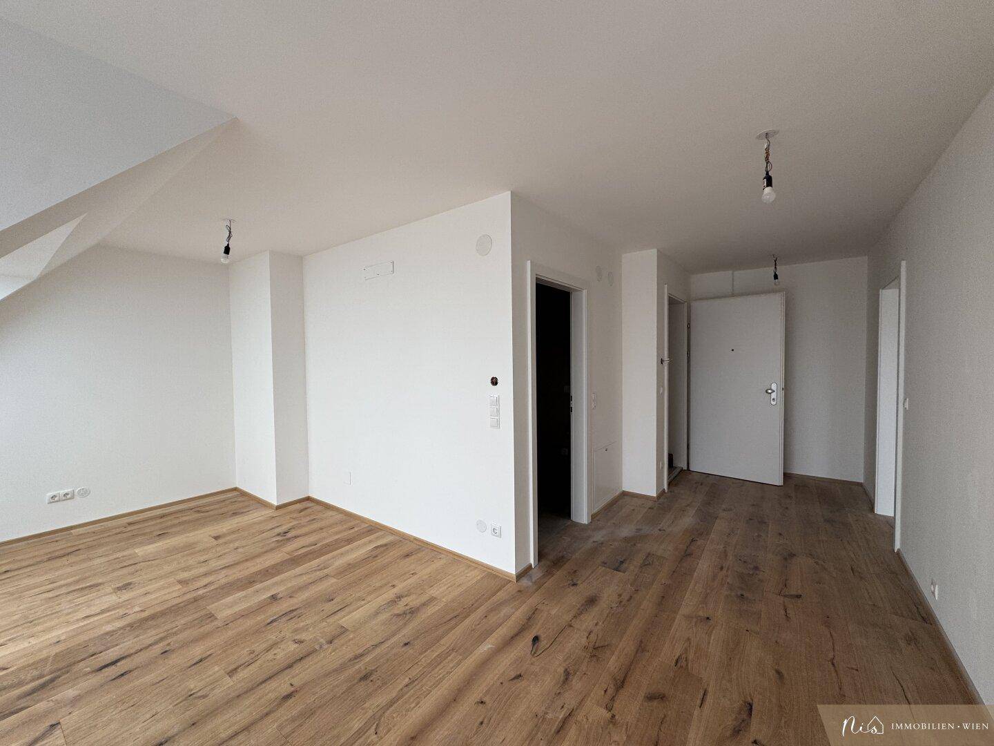 Heller Eingangsbereich mit Holzboden und mehreren Türen, der zu verschiedenen Räumen führt.