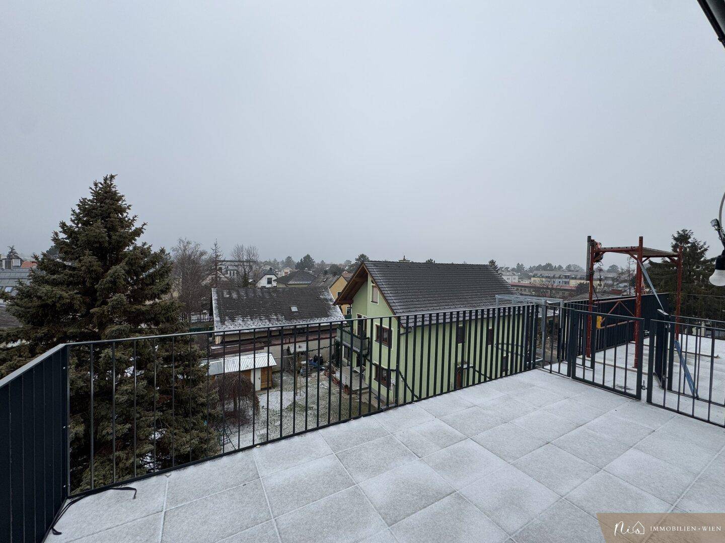Dachterrasse mit Fliesenboden und Blick auf die verschneite Umgebung im Winter.