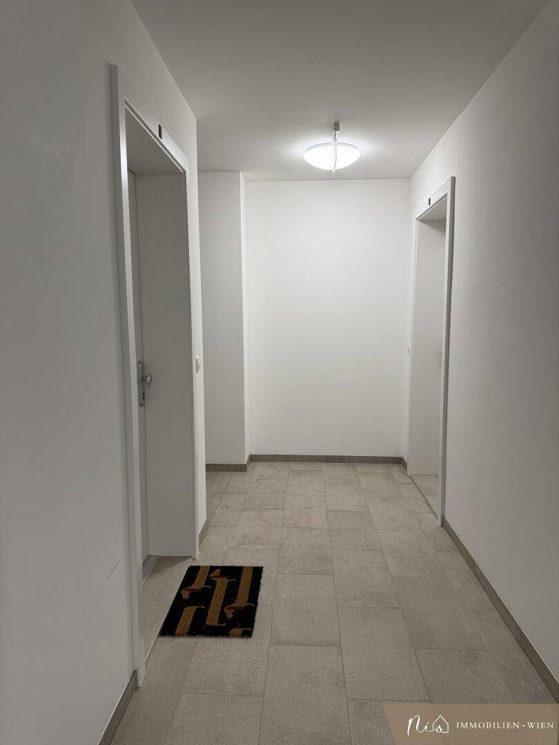 Heller Eingangsbereich mit Fliesenboden und Zugang zu Wohnungen und Treppenhaus.