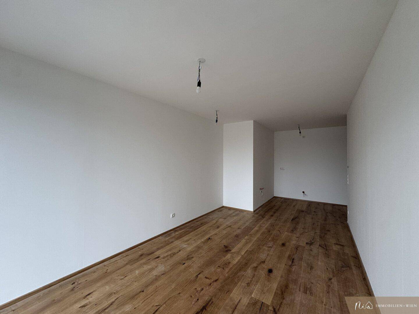 Unmöbliertes Schlafzimmer mit Holzboden und viel Tageslicht.