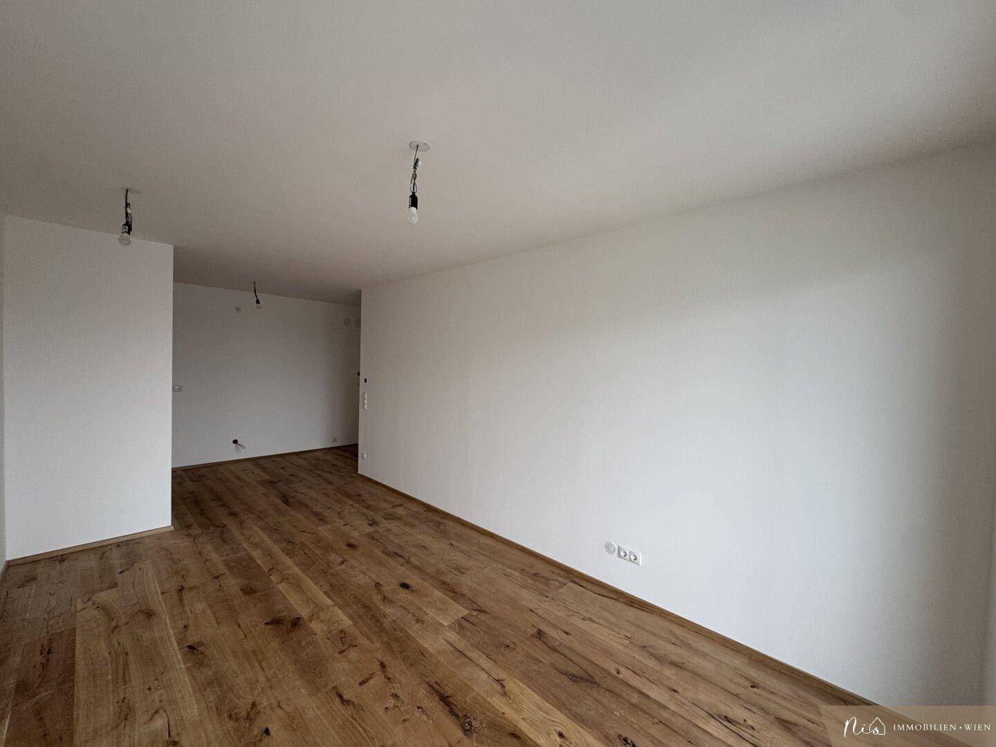 Geräumiger, unmöblierter Raum mit hellem Holzboden und weißen Wänden.