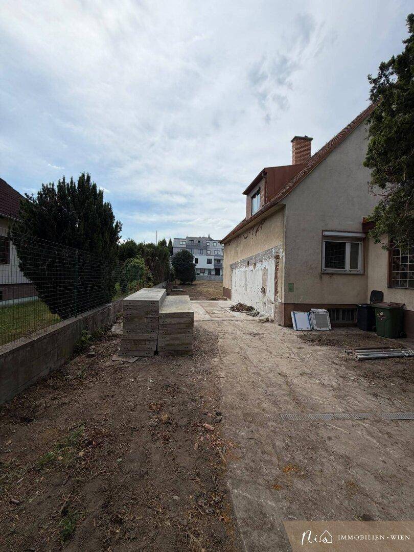 Seitenansicht des Hauses mit gestapelten Betonplatten und einem Blick auf das Nachbargebäude.