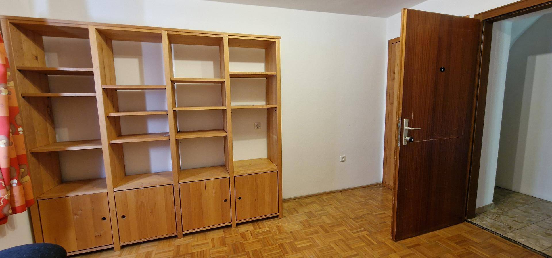 Raum mit großem Holzregal und Parkettboden, ideal für Bücher oder Dekoration.