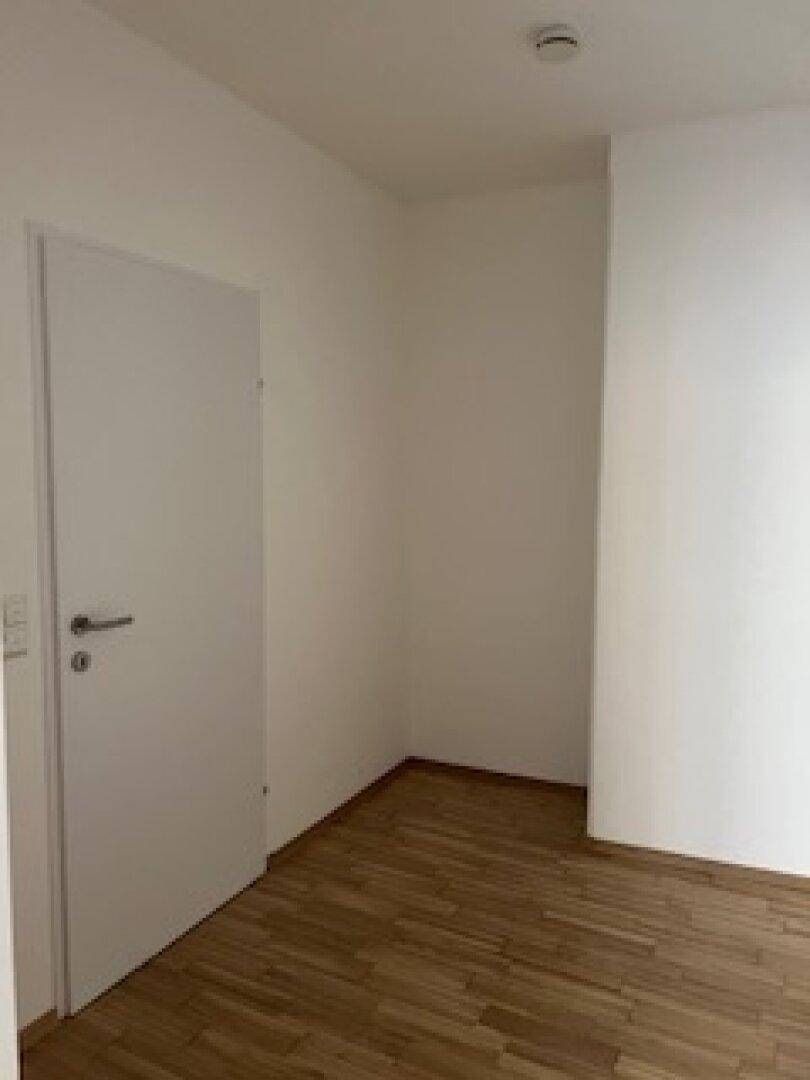 Leerer Raum mit hellem Holzfußboden und einer weißen Tür, bereit zur individuellen Gestaltung.