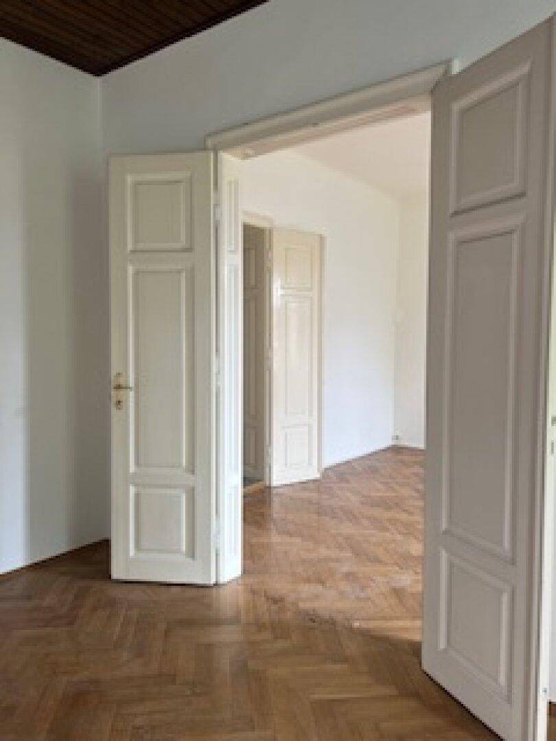 Detailansicht des Wohnzimmers mit Fischgrätparkett und klassischer Flügeltür.