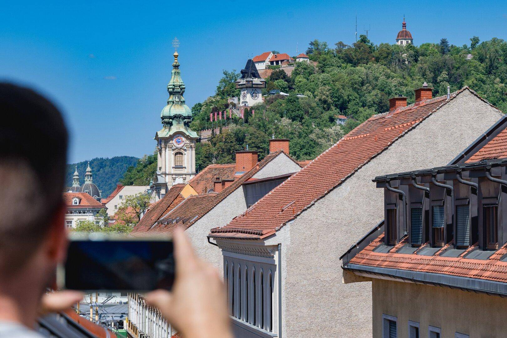 Panoramablick auf die Stadt mit historischen Gebäuden und grünen Hügeln.