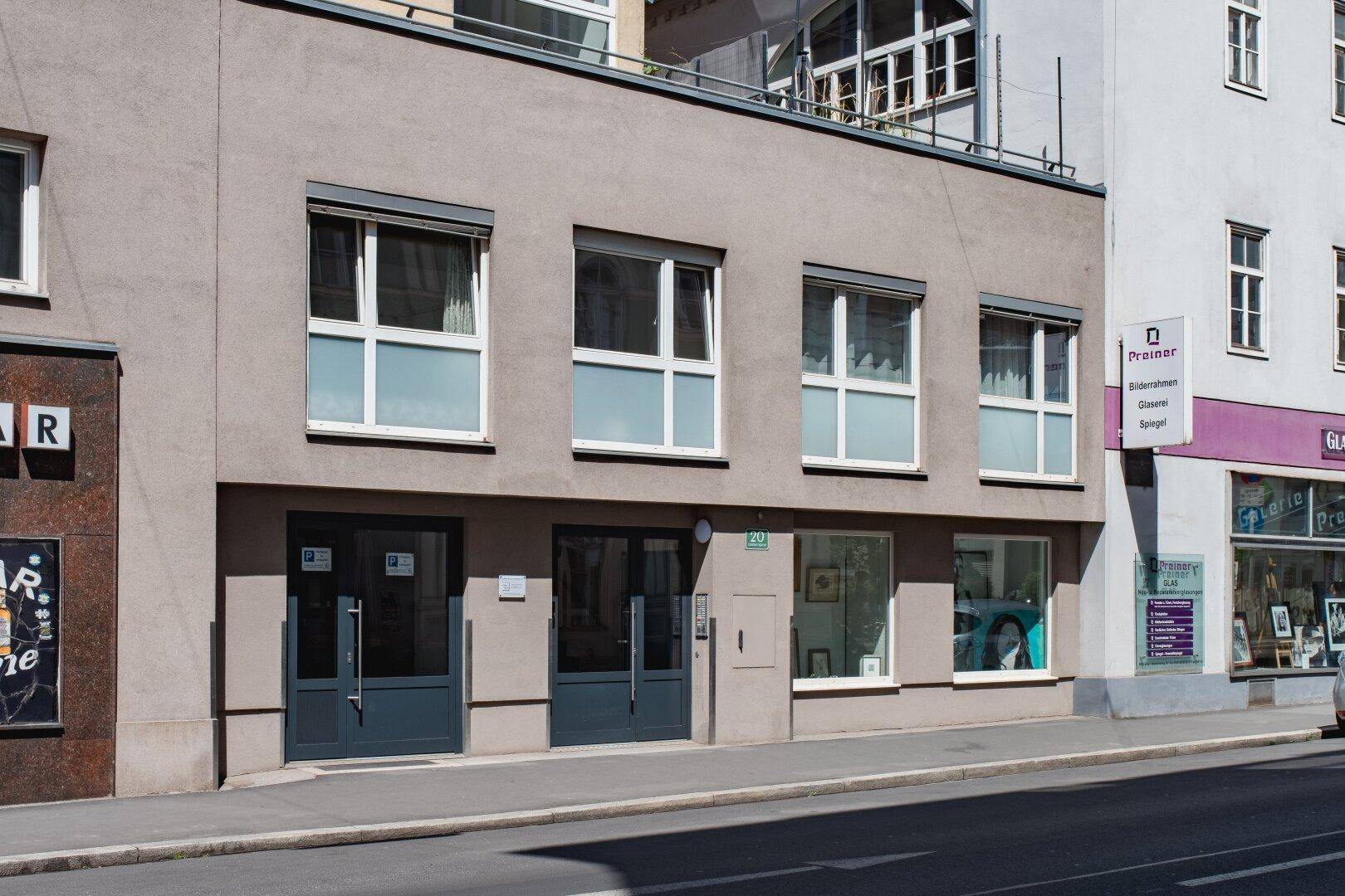 Moderne Gebäudefassade mit großen Fenstern und Geschäften im Erdgeschoss.