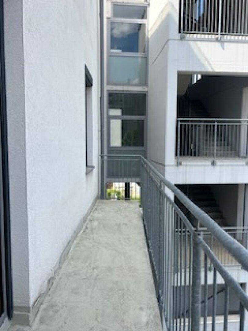 Außenseite des Gebäudes mit einem begehbaren Balkon und einer verglasten Struktur.