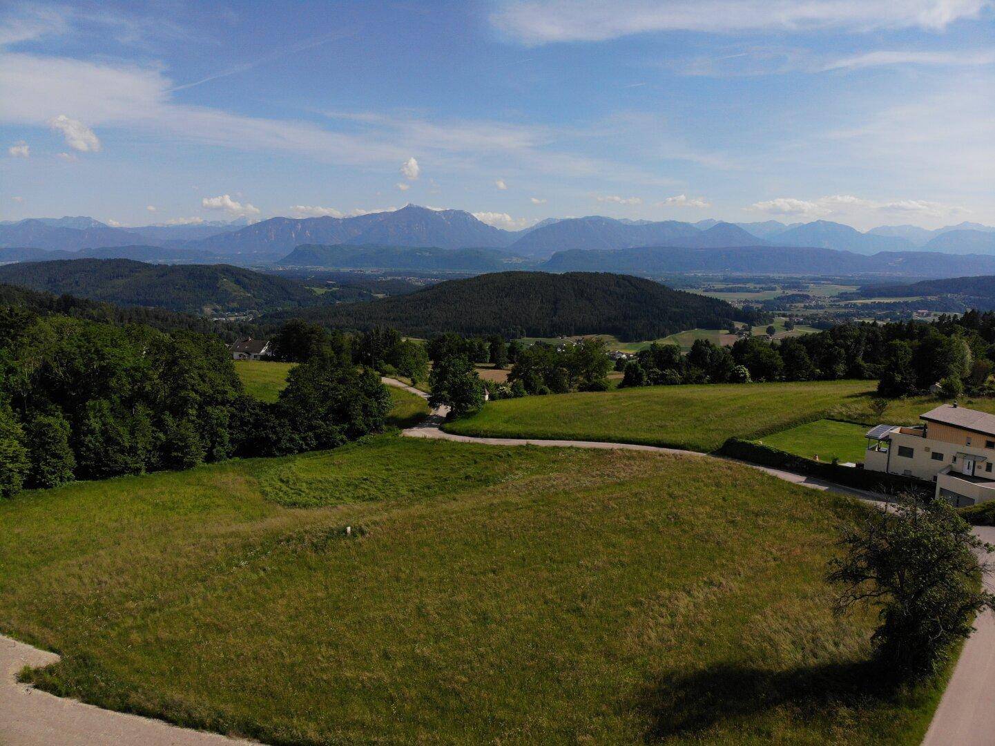 Panoramablick auf ein großes Grundstück mit umliegender Natur und einem beeindruckenden Alpenpanorama.