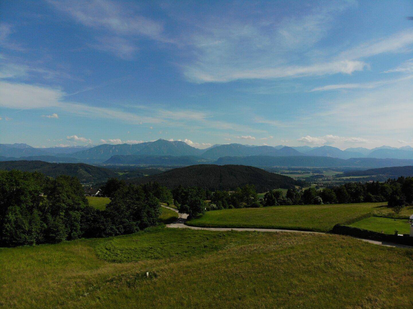 Panoramablick auf ein großes Grundstück mit umliegender Natur und einem beeindruckenden Alpenpanorama.