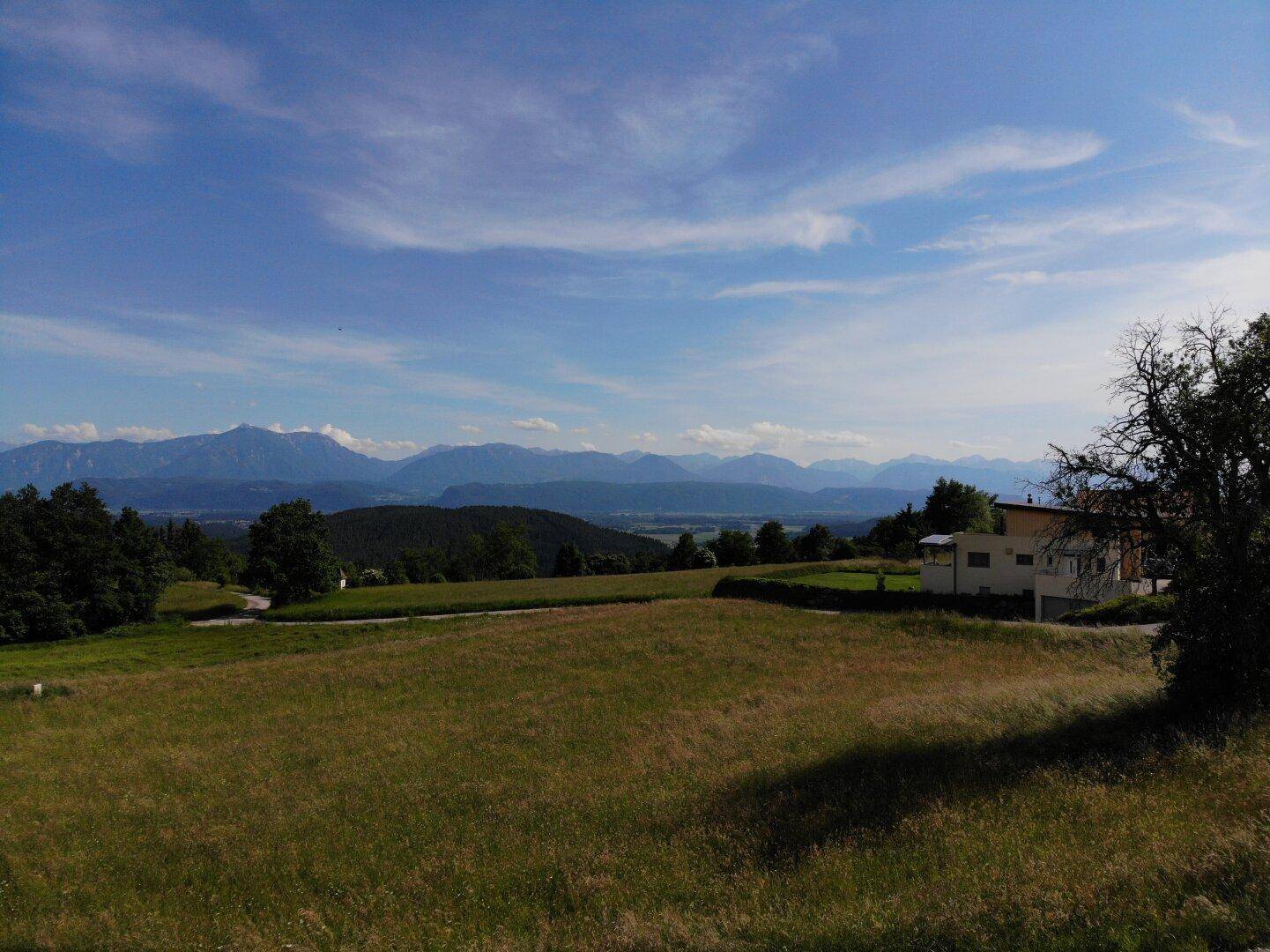 Grundstück mit weitem Blick über die grüne Landschaft und die beeindruckenden Berge am Horizont.