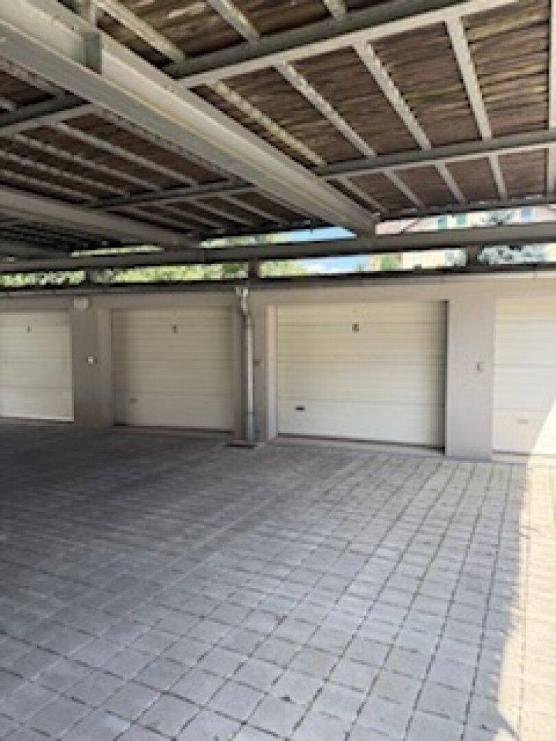 Garagenreihe unter einer überdachten Struktur mit gepflastertem Boden und guter Beleuchtung.