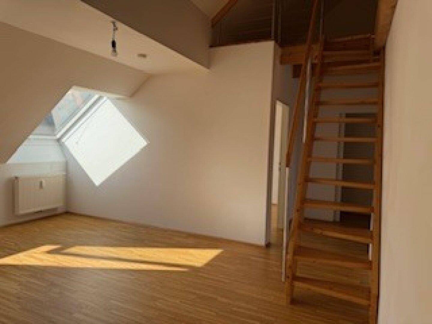 Heller Wohnraum mit Holzboden, Dachschrägen und einer Holztreppe, die zu einer oberen Ebene führt.