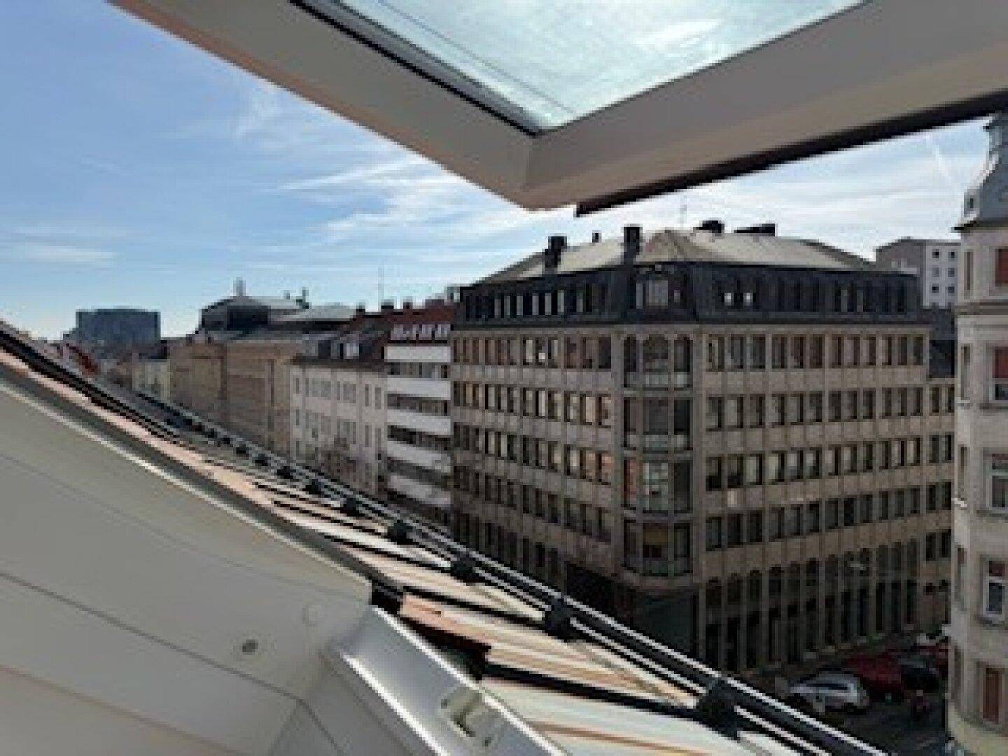 Weitblick über eine belebte Stadtstraße mit historischen Gebäuden und einem klaren Himmel.