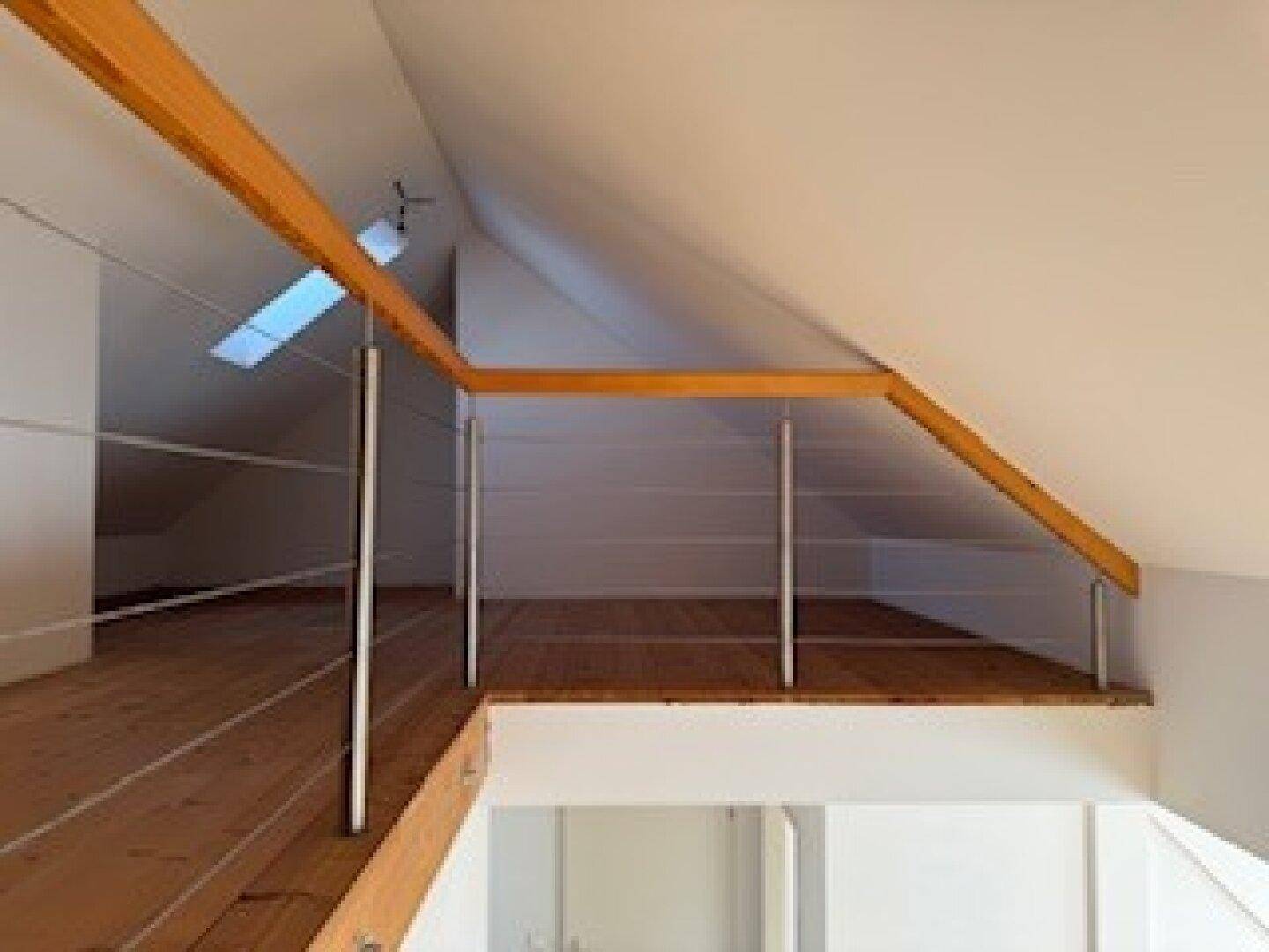 Helle Galerie im Dachgeschoss mit Holzboden, modernem Geländer und Dachfenster.