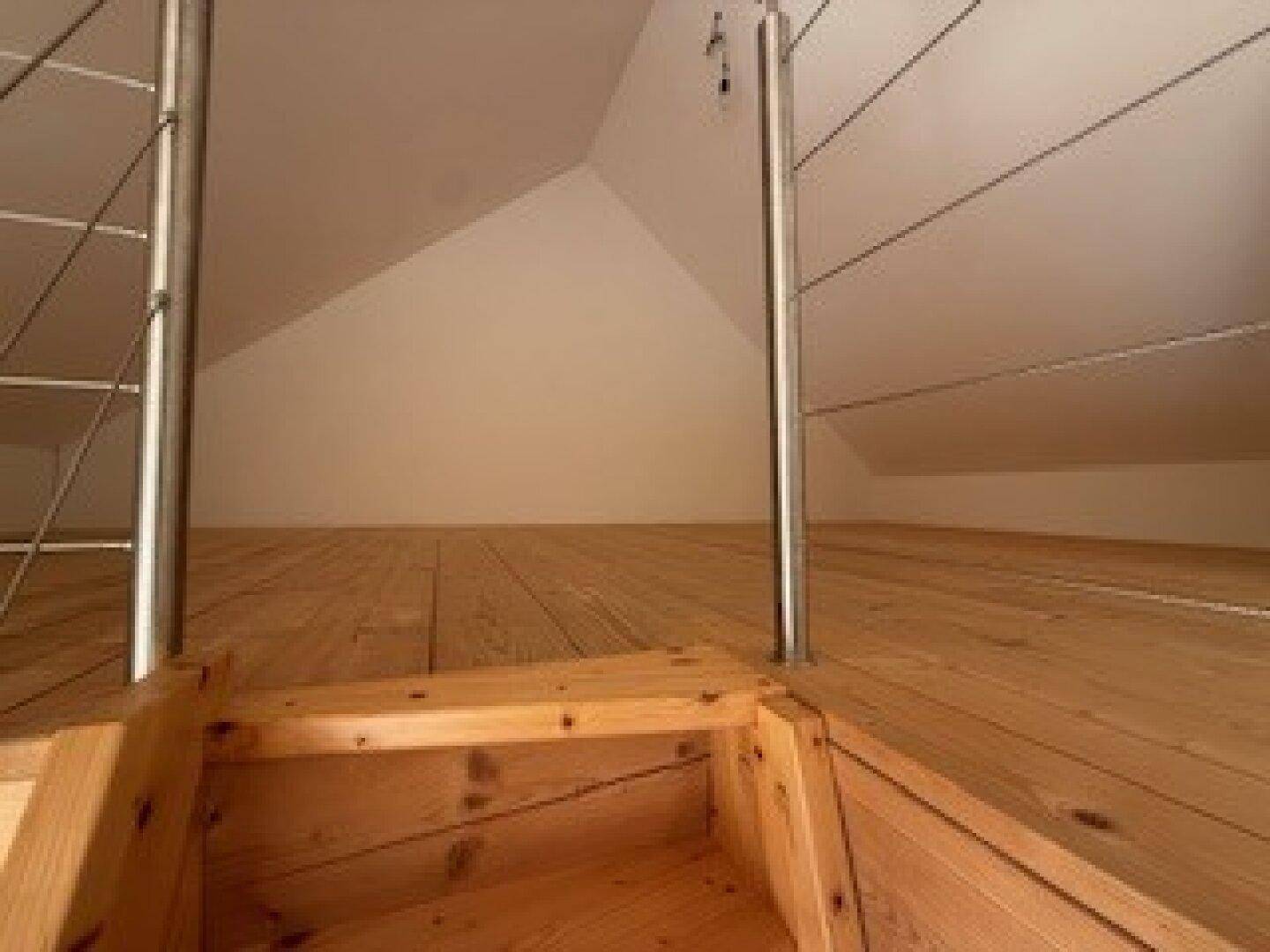 Detailansicht des Holzdielenbodens und des modernen Geländers im hellen Dachgeschoss.