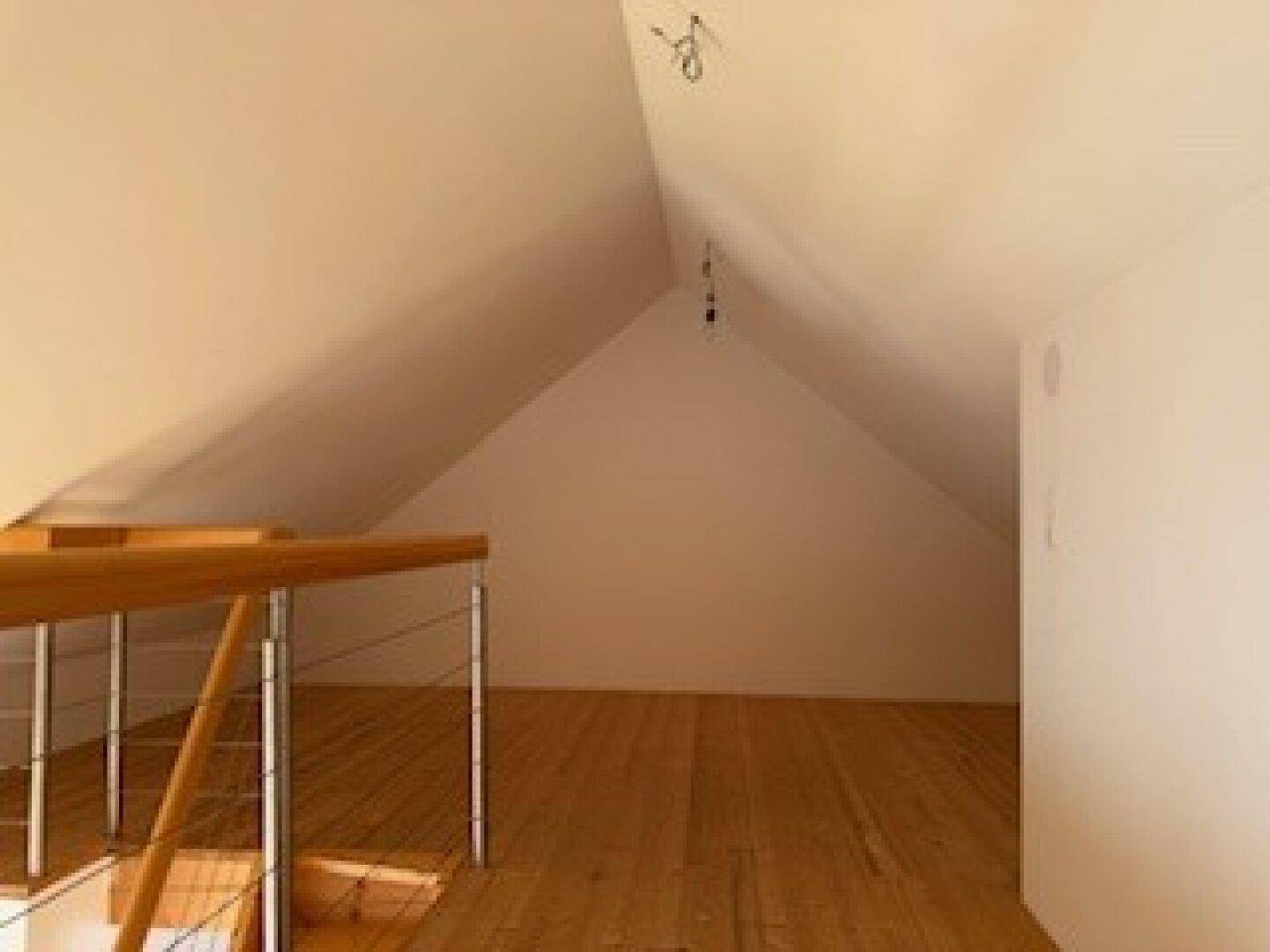 Geräumiger Dachbodenbereich mit Holzdielenboden und hohen, schrägen Decken.
