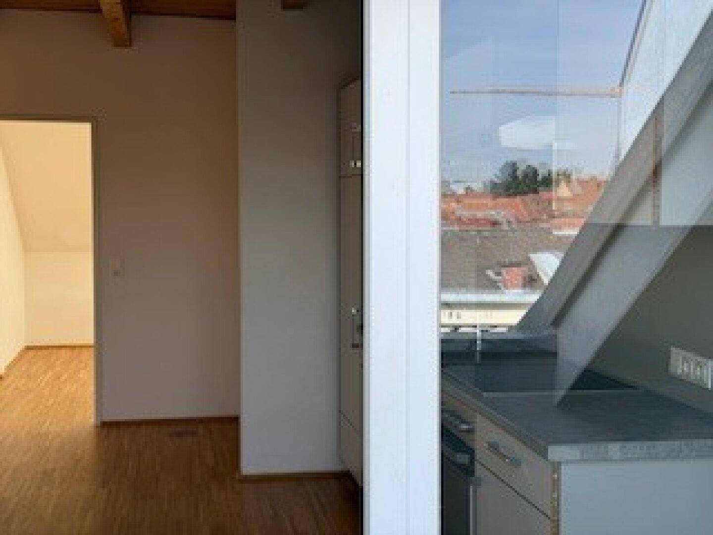 Moderne Küche mit Spüle am Fenster und Blick auf die Stadt, angrenzend an einen Raum mit Holzboden.