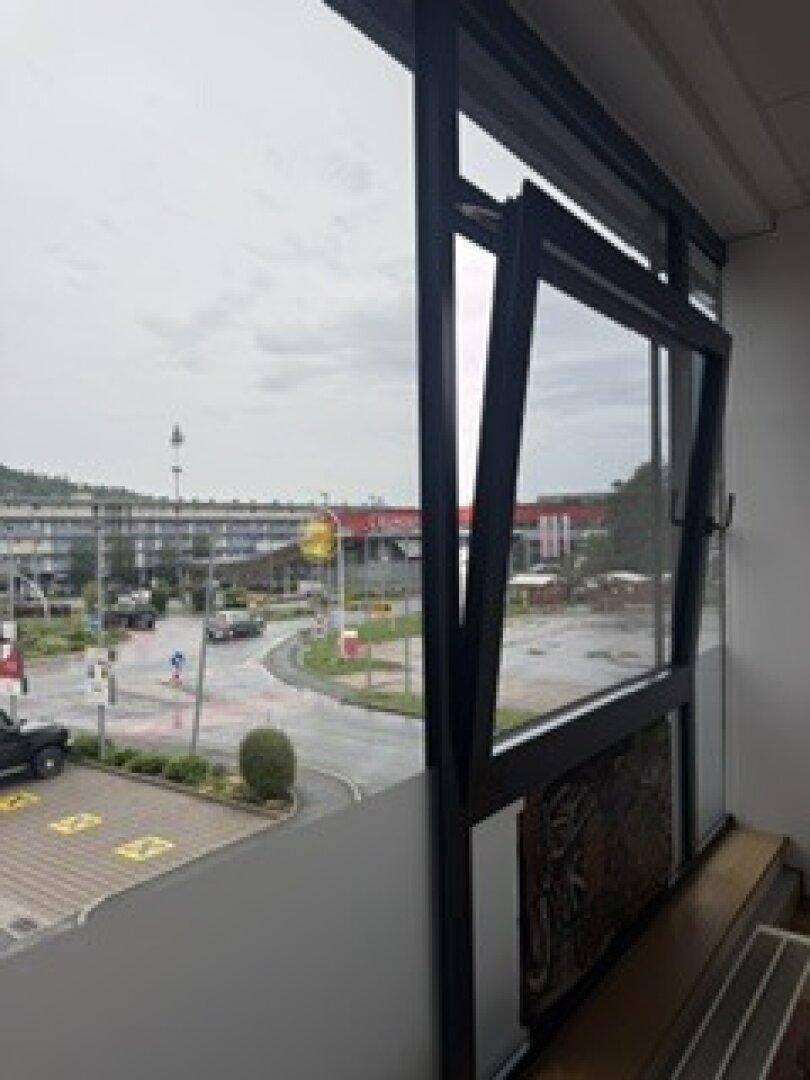 Blick aus einem Bürofenster auf eine Straße mit Verkehr und weitere Gebäude in der Ferne.