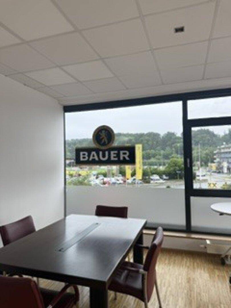 Moderner Büroraum mit einem Konferenztisch und großen Fenstern, die viel Tageslicht hereinlassen.
