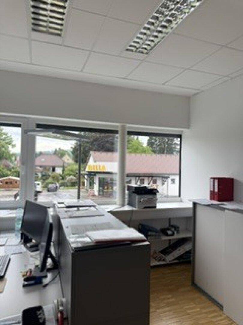 Helles Büro mit mehreren Arbeitsplätzen und großen Fenstern, die einen Blick nach draußen ermöglichen.