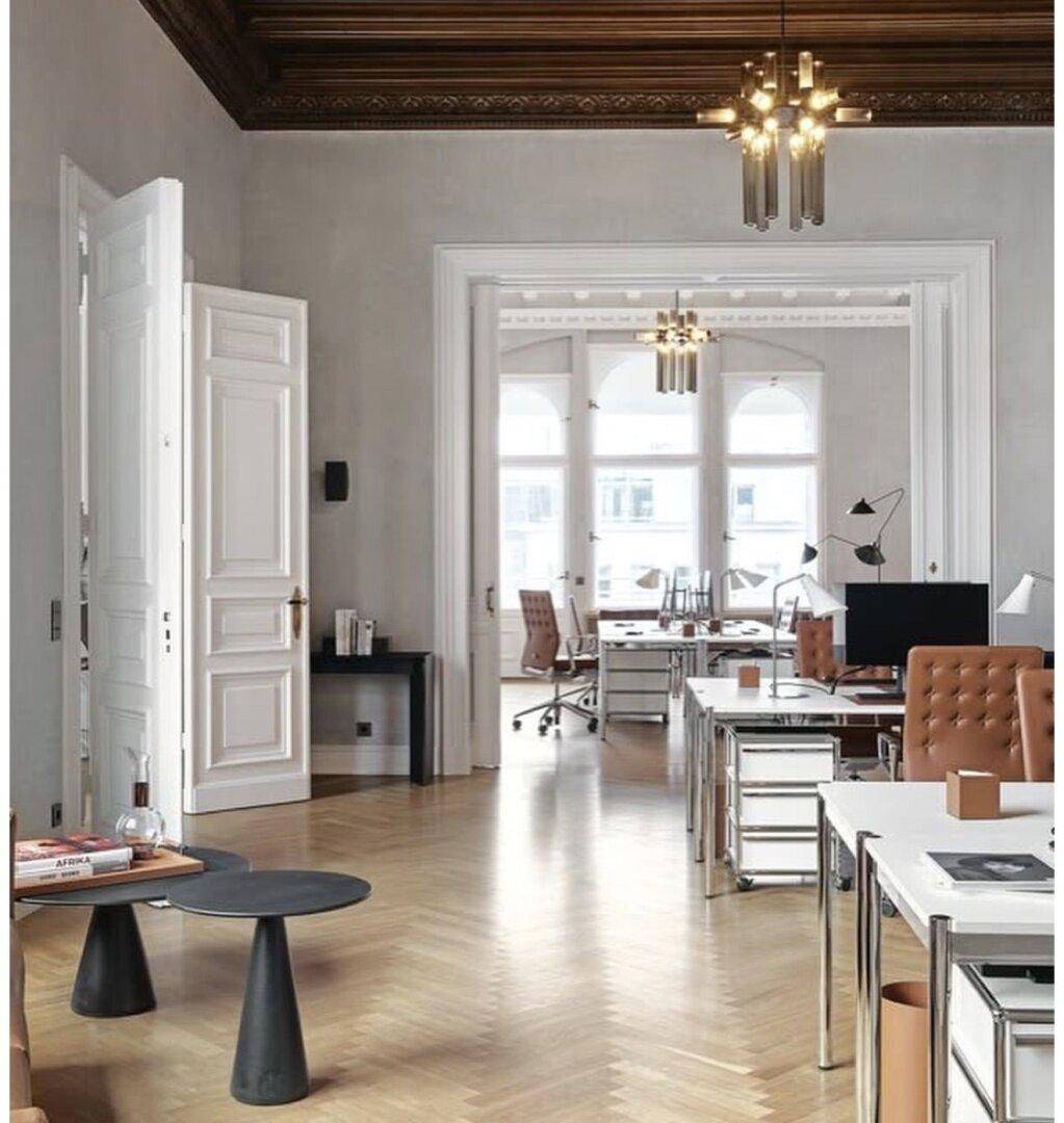 Helles Büro mit Fischgrätparkett, hohen Decken und modernen Arbeitsplätzen.
