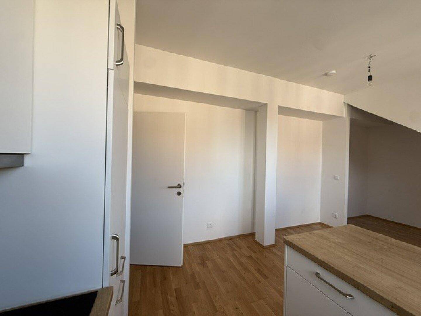 Leerer Raum mit Holzboden und weiß gestrichenen Wänden, bereit zur individuellen Gestaltung.