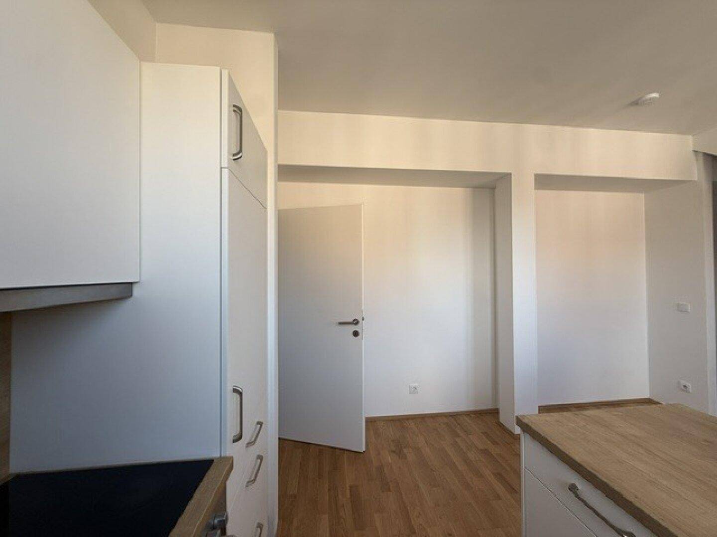 Leerer Raum mit Holzboden und weiß gestrichenen Wänden, bereit zur individuellen Gestaltung.