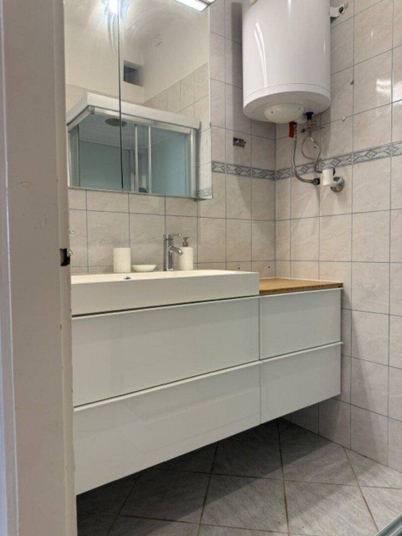Moderner Waschtisch mit Einzelwaschbecken, Spiegelschrank und gefliesten Wänden im Badezimmer.