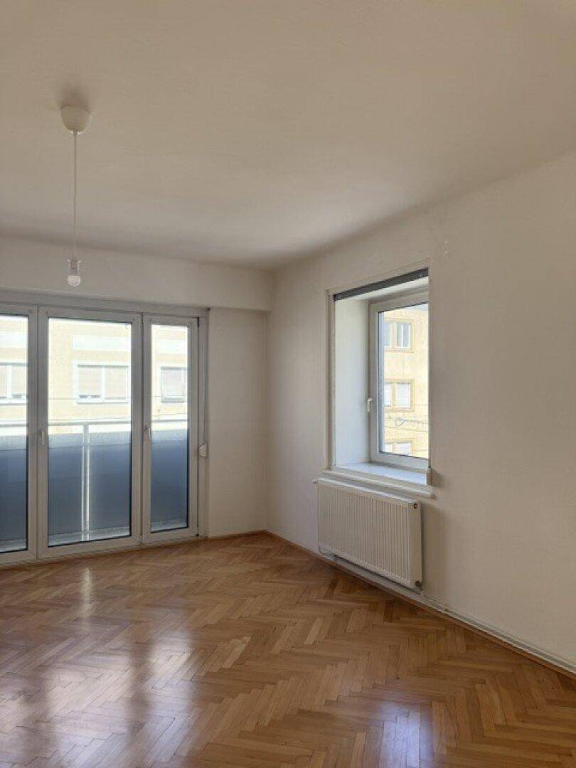 Heller Raum mit Fischgrätparkett, großen Glastüren und einem zusätzlichen Fenster.