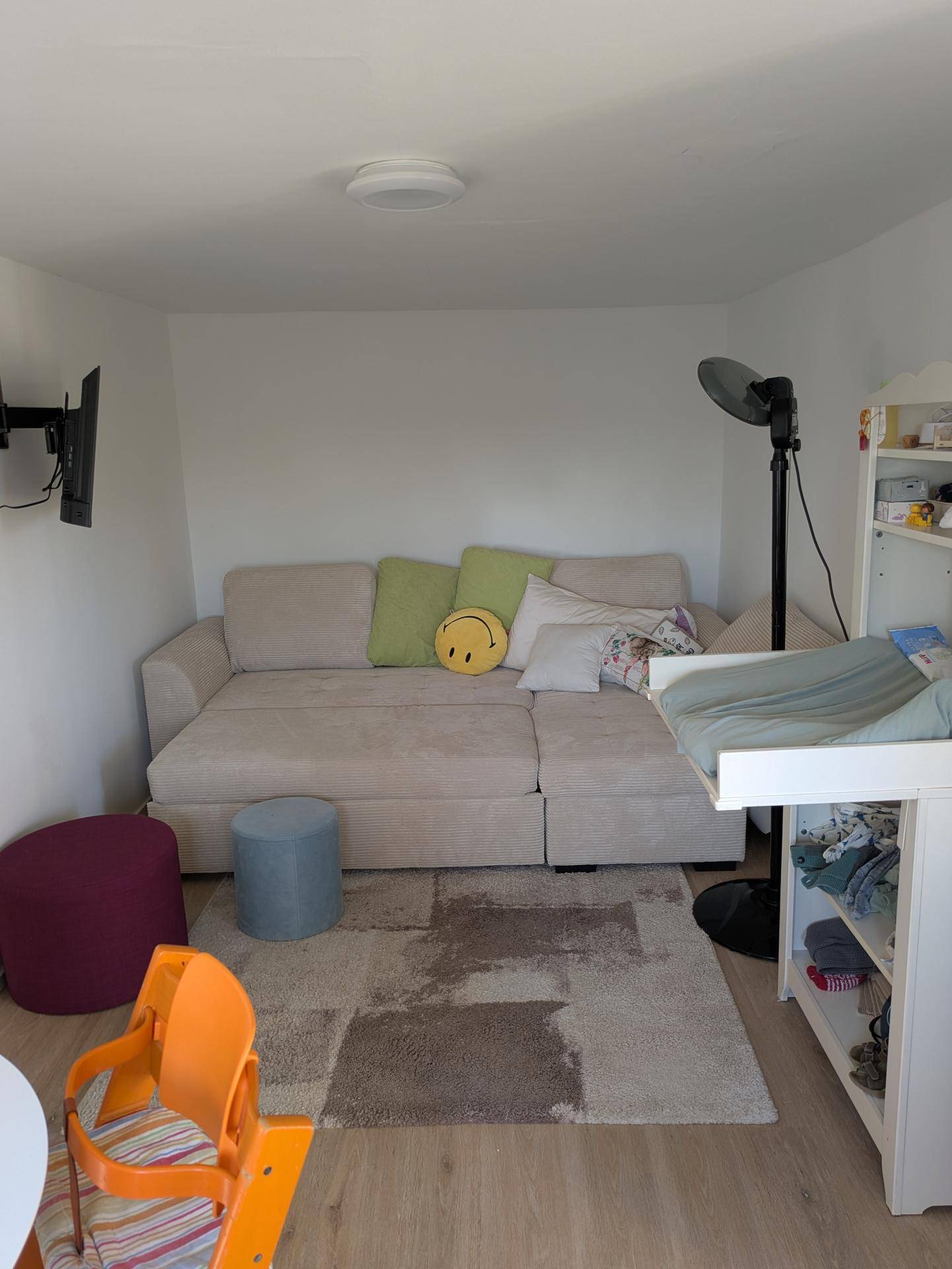 Heller Wohnbereich mit Sofa, Wickeltisch und Teppichboden, ideal für Familien.