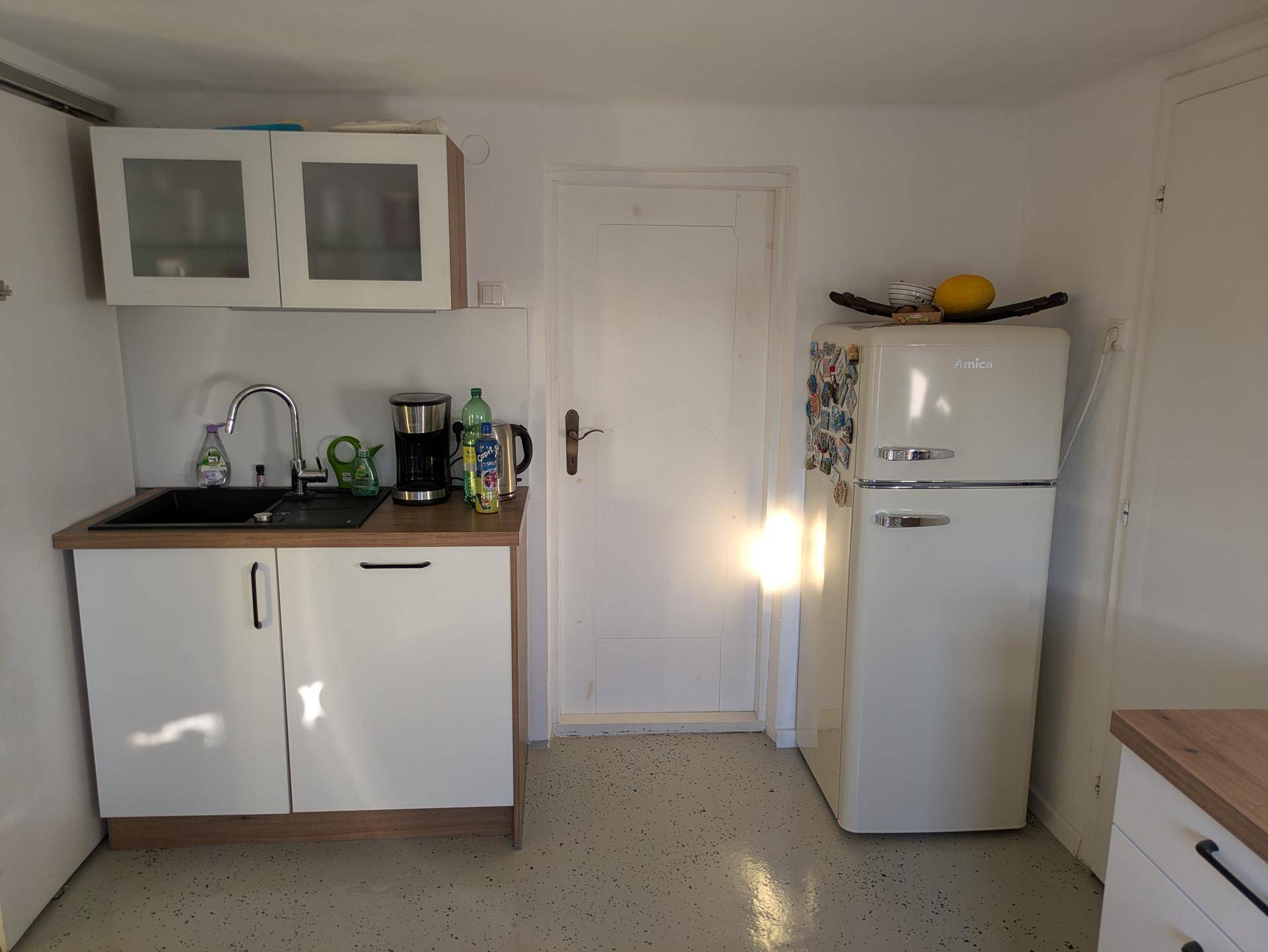 Küchenzeile mit Spüle, Unterschränken und einem freistehenden Retro-Kühlschrank.