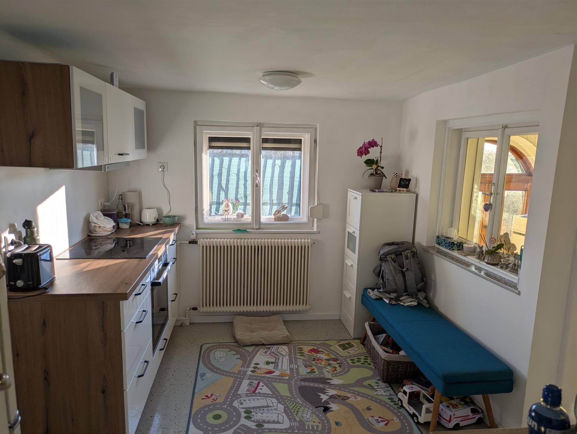 Funktionale Küche mit Holz- und weißen Schränken, Induktionskochfeld und Fensterblick.