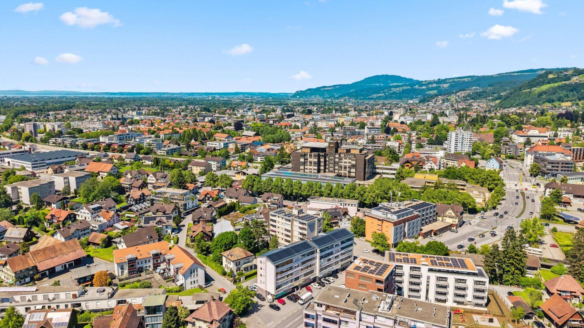 Breiter Panoramablick über eine Stadtlandschaft mit Wohngebieten und weitem Horizont unter blauem Himmel.
