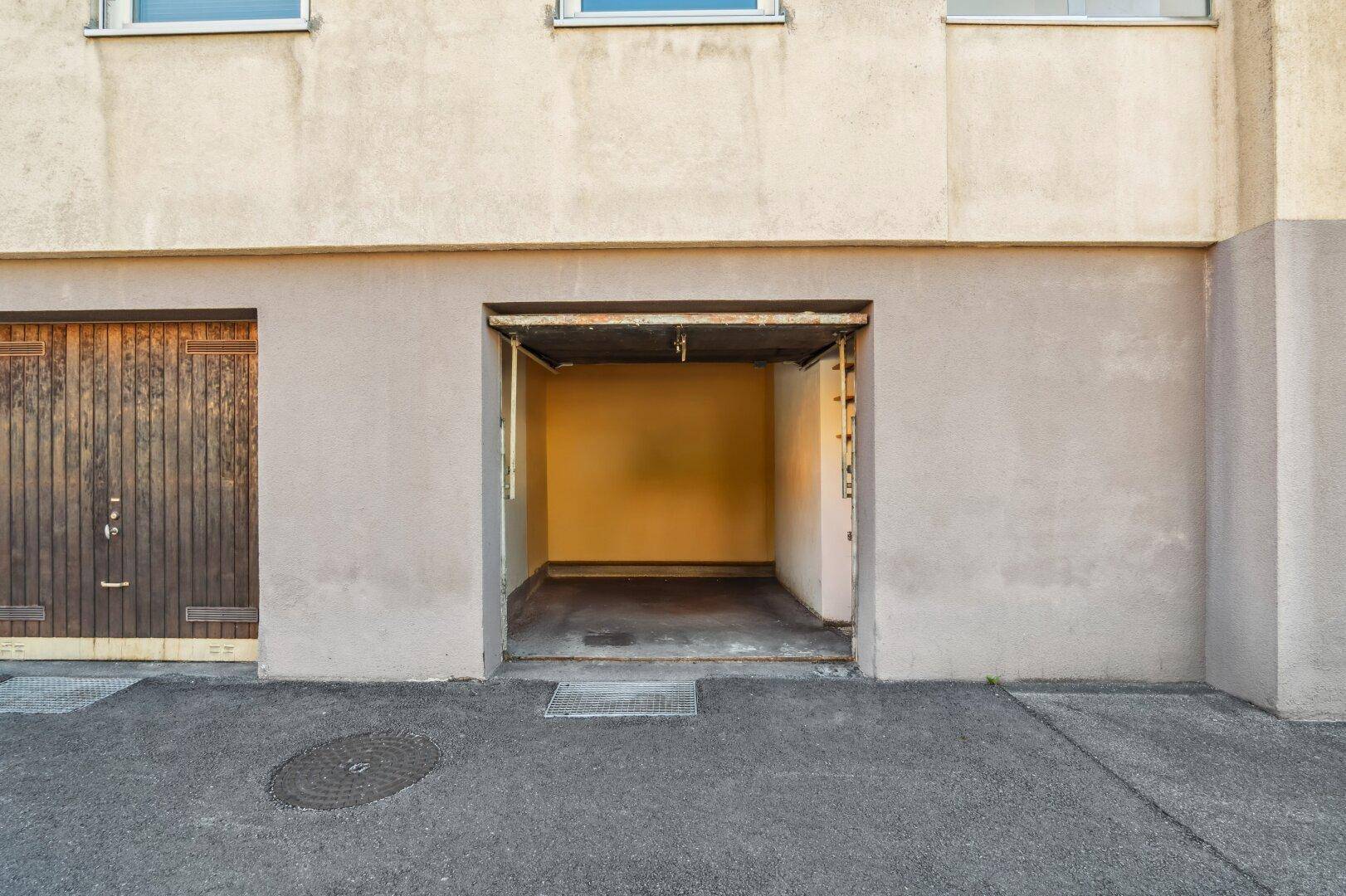 Einzelgarage mit offenem Tor und Zufahrt von der Straße.
