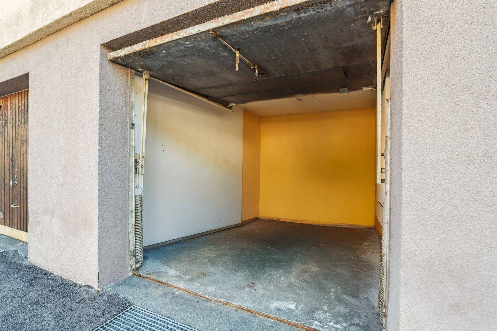 Einzelgarage mit offenem Tor und Betonboden.